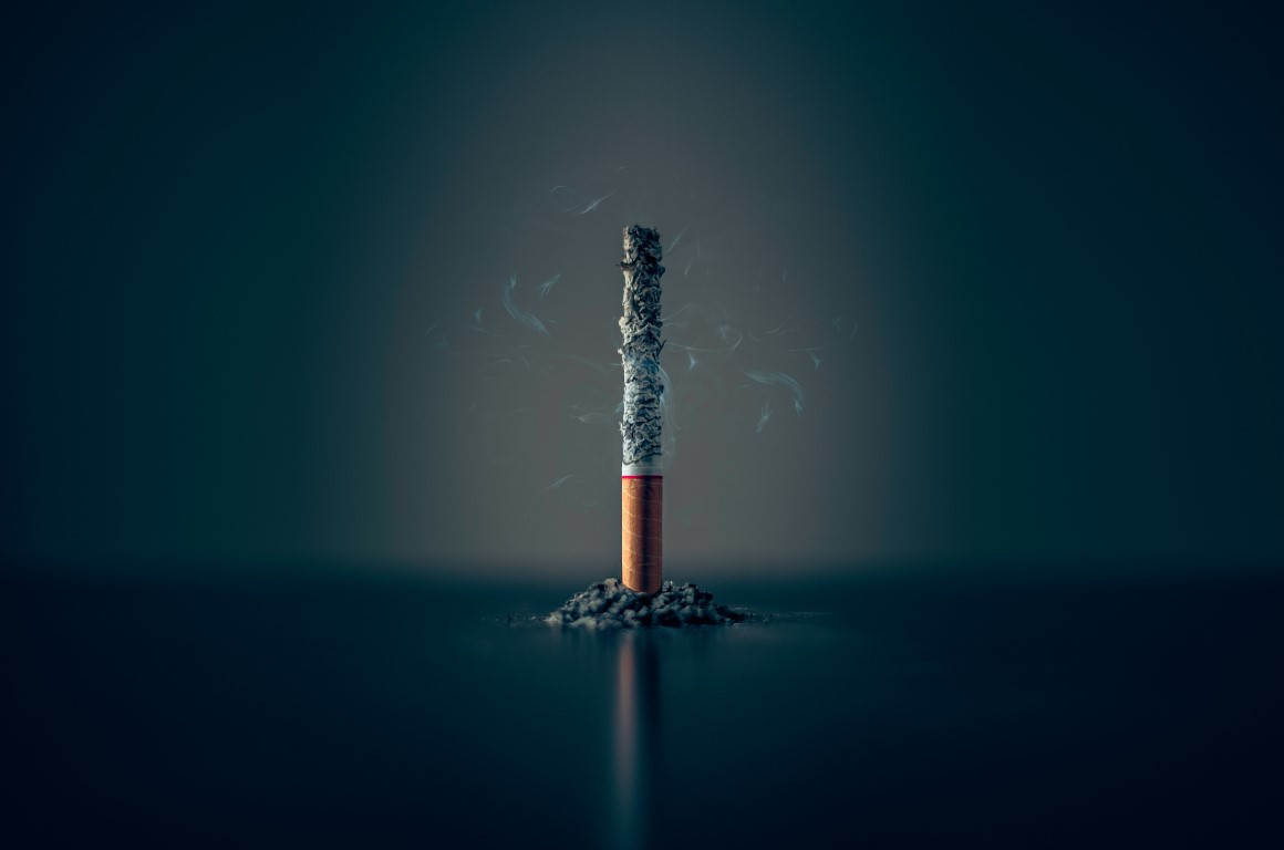 Image of a cigarette stood on it's end, burnt through